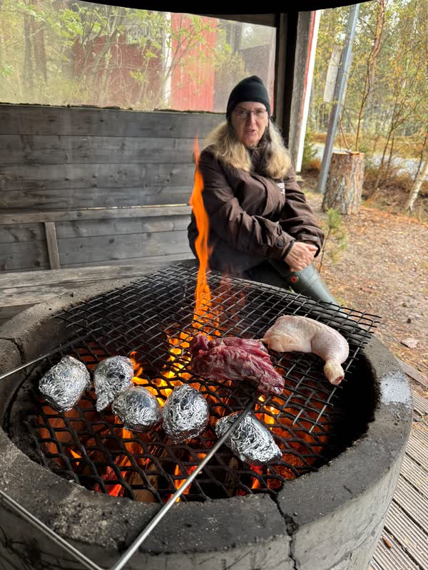 Meat and foil-wrapped potatoes on the grate over the open fire inside the kota