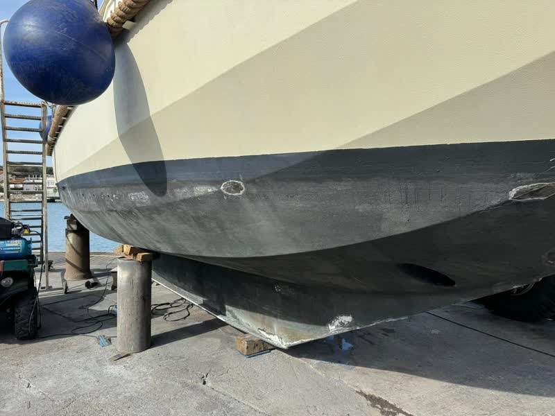 The side of the Gypsy Life’s hull, its double chine above the fresh antifouling